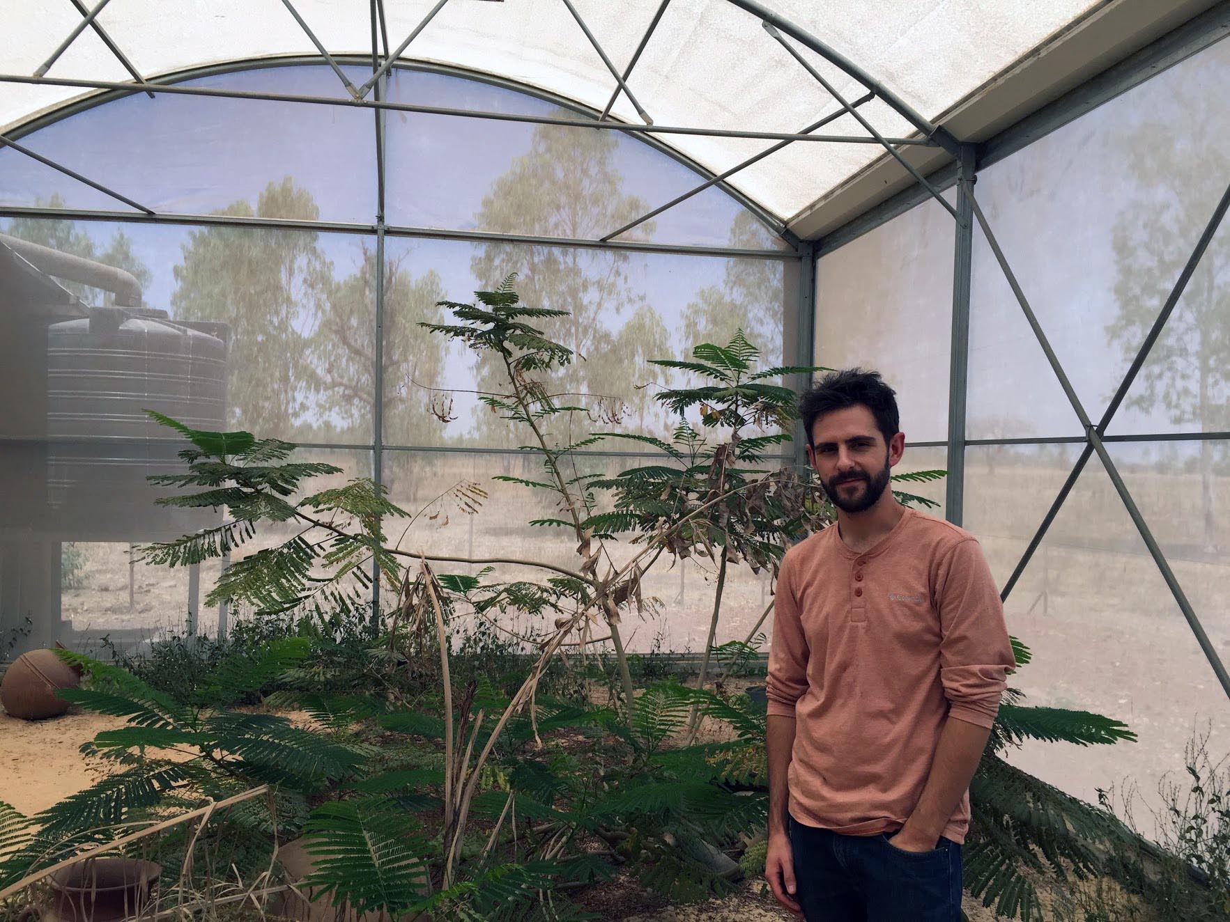  UMD Entomologist Brian Lovett, one of the lead authors of the 2019 AAAS Newcomb Cleveland Prize-winning paper, stands inside MosquitoSphere, a roughly 6,550 square-foot screened-in structure in Burkino Faso, built to simulate a village setting that includes plants, huts, small pools of water and a food source for mosquitos. Photo credit: Etienne Bilgo (Click image to download hi-res version.)