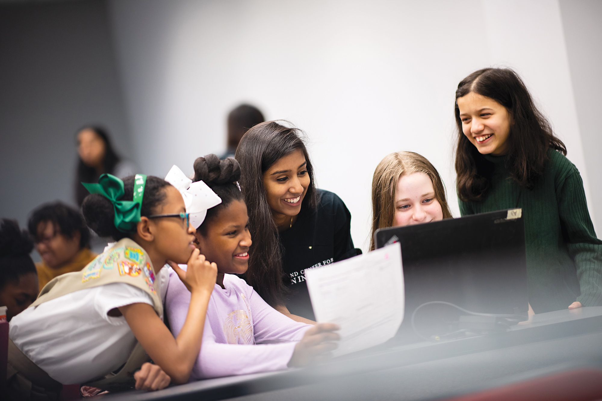 Utsa Santosh, center, with four elementary-age girls gathered around a laptop.