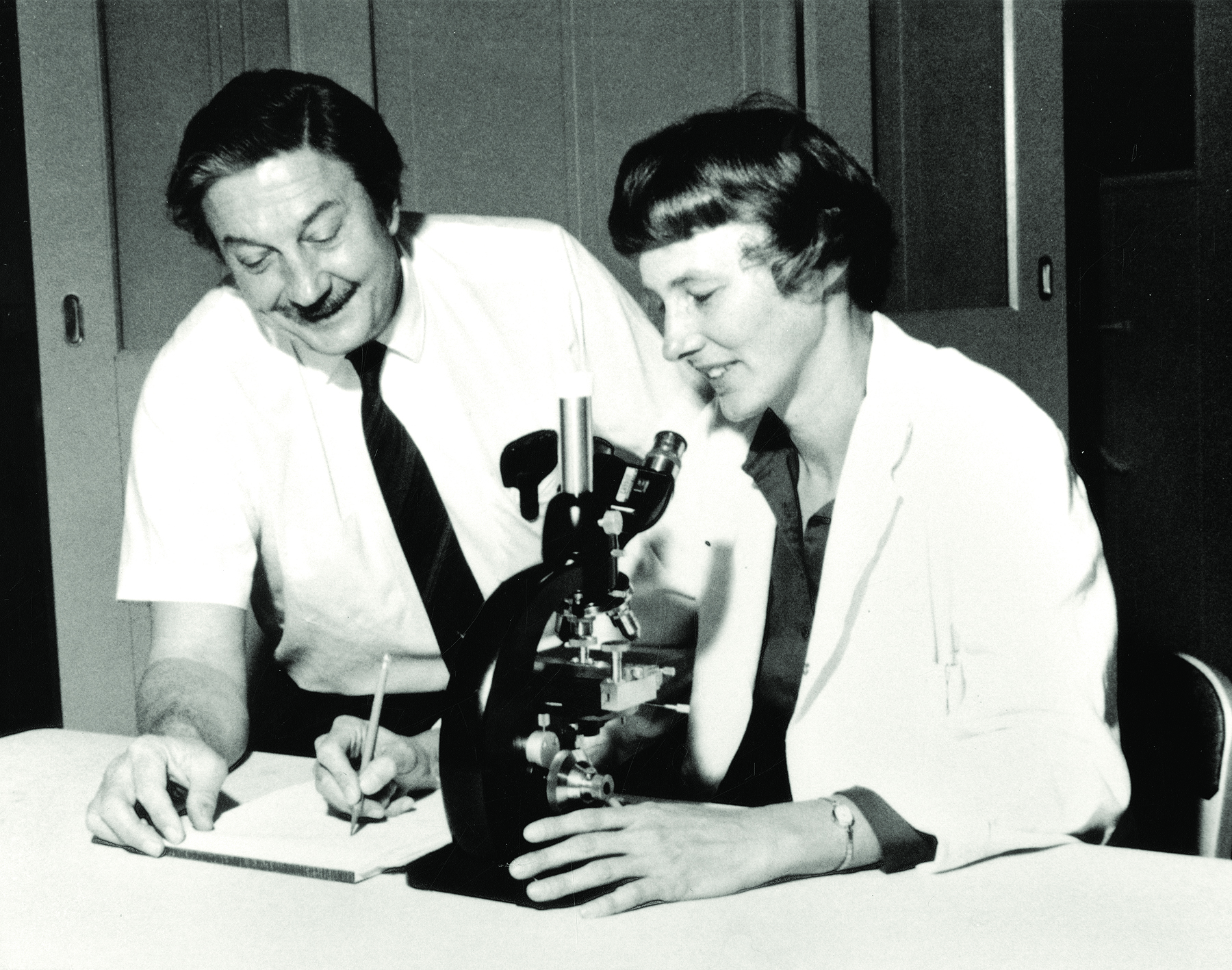  black and white photo Bob Hubner with Janet Hartley working at a microscope at the NIH in 1960.