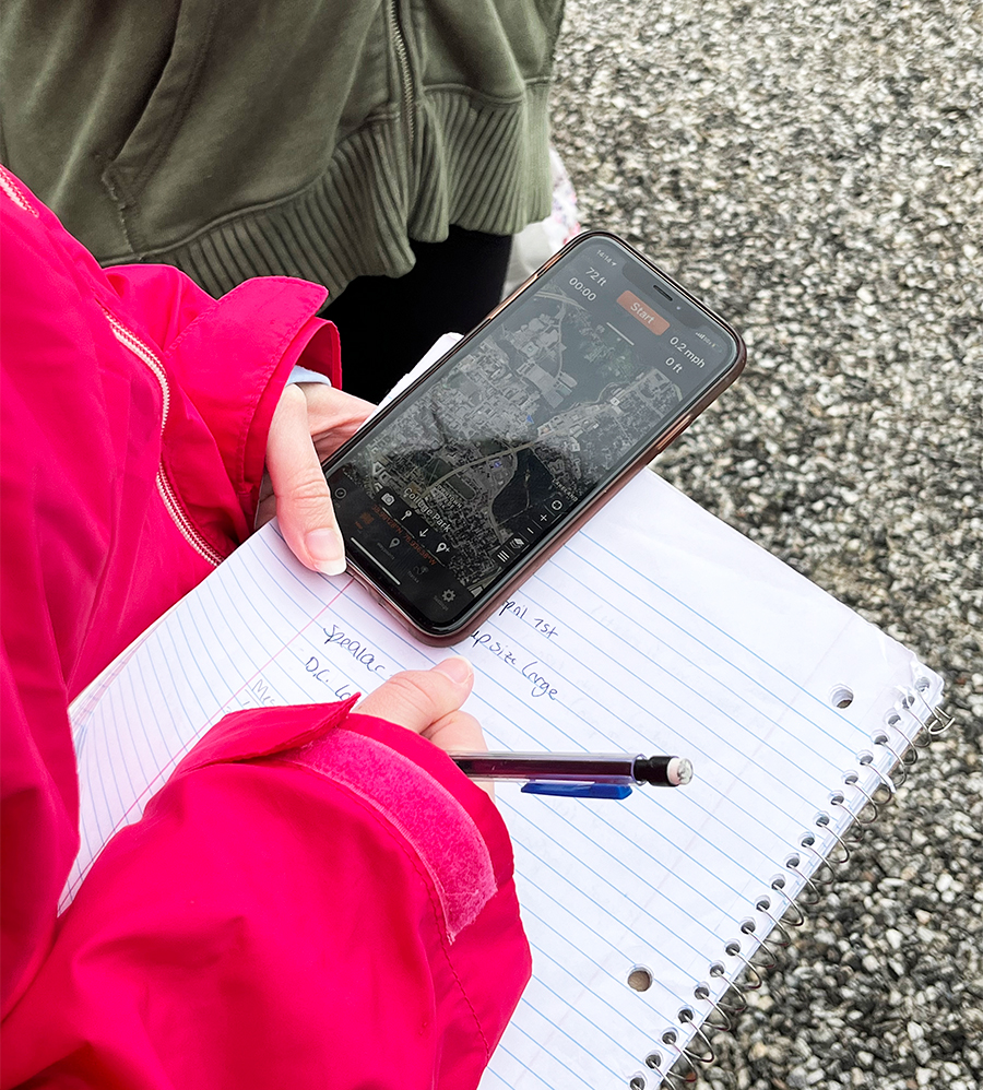 A student holding a phone and notebook
