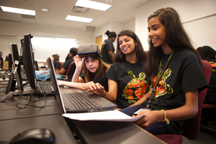 (L-R) Computer Science Connect participant Kayla Newby, teaching assistant Stacy George and participant Isha Santhosh use an Oculus Rift headset to demo the virtual reality game the two students created. Credit: John T. Consoli (Click image to download hi-res version.)